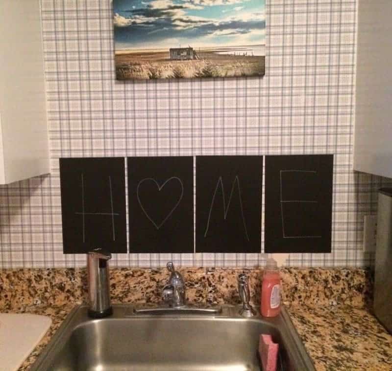 Black chalkboard stickers spelling "home" above kitchen sink.