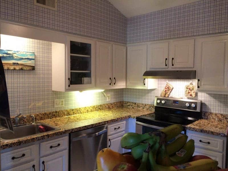 Granite film on countertops in kitchen with stainless appliances and white cabinets.