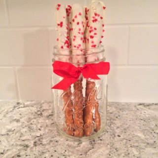 White chocolate dipped Valentine's Day pretzel rods with heart sprinkles.