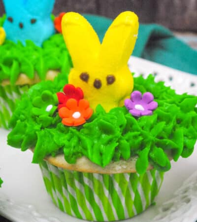 Peeps cupcakes with green buttercream frosting and icing flowers.