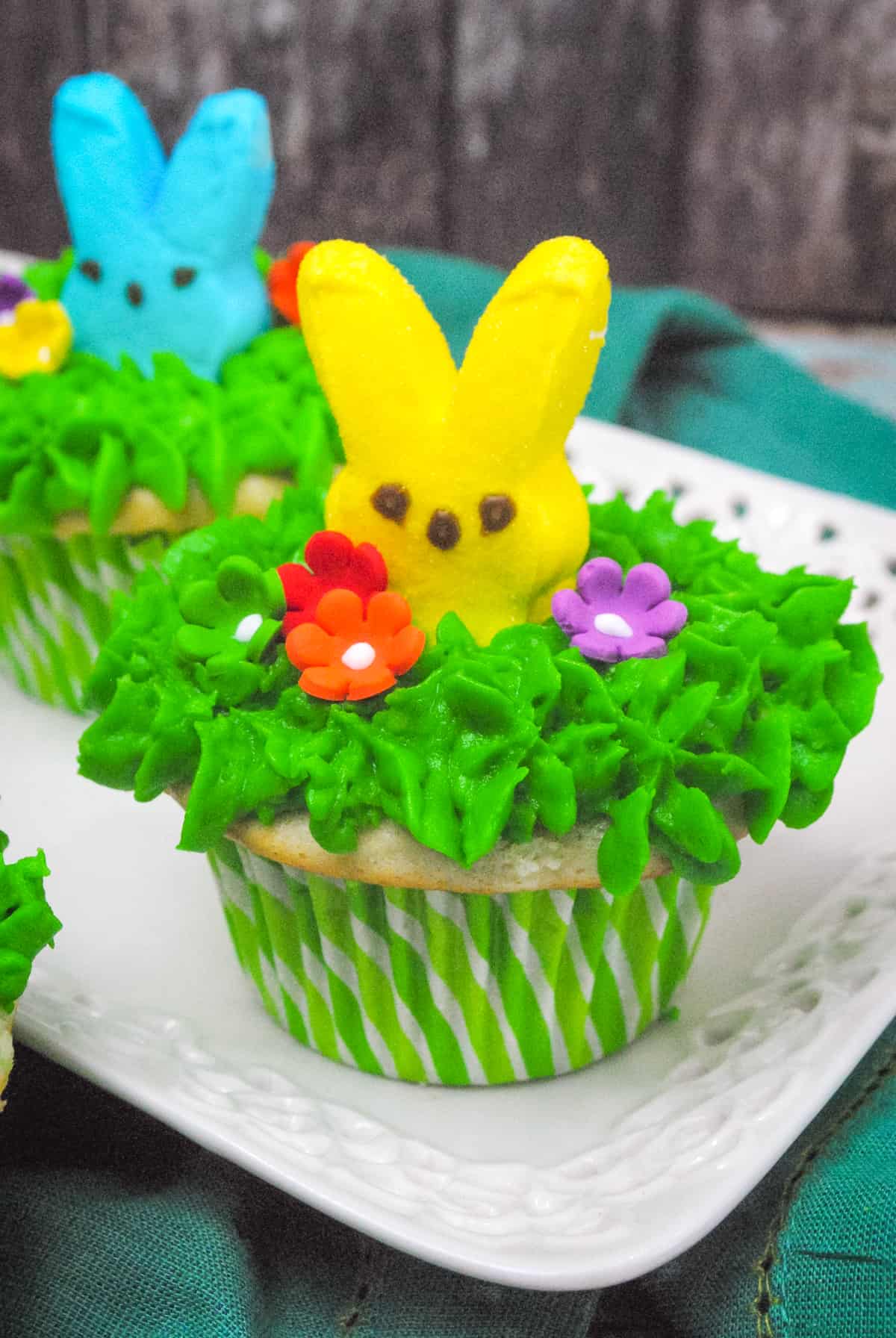 Peeps cupcakes with green buttercream frosting and icing flowers.