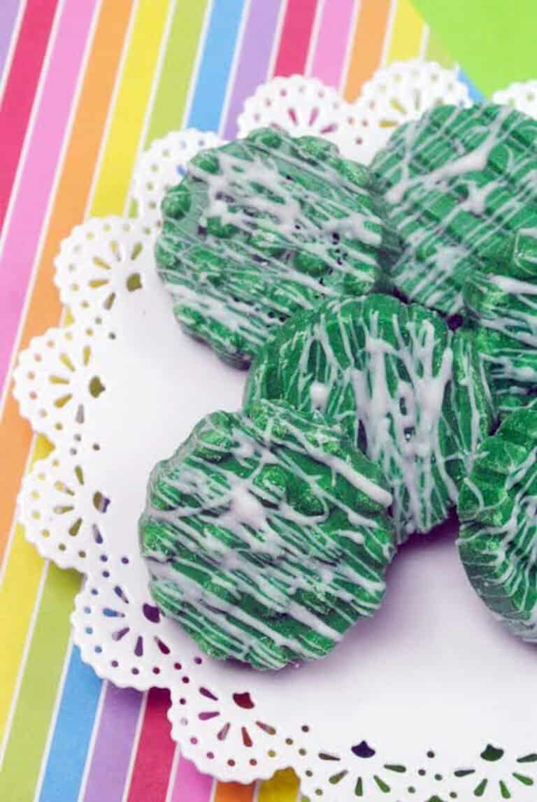 Candy-Dipped Green oreos with white chocolate drizzle on rainbow background.