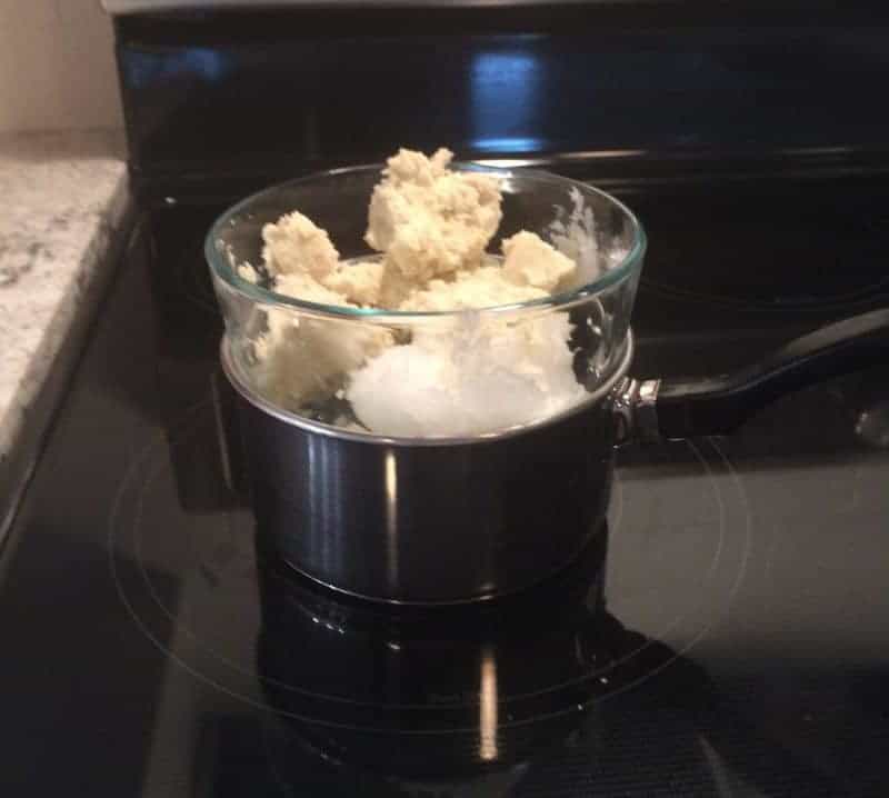 Shea butter and coconut oil in bowl of a double broiler on stovetop.