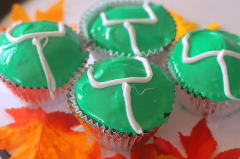 Vanilla cupcakes decorated with green icing and white icing goalposts.