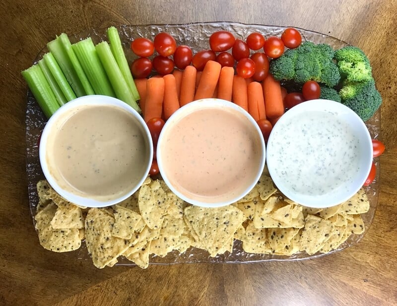 Platter with 3 ranch-based dips, tortilla chips, and fresh veggies.