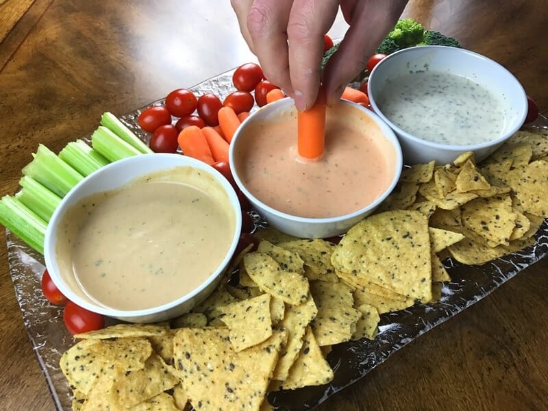 Hand dipping baby carrot into dip.