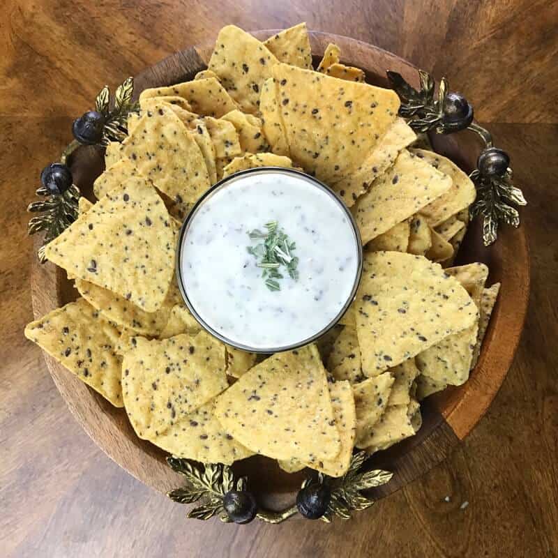 Bacon ranch dip in bowl surrounded by tortilla chips.