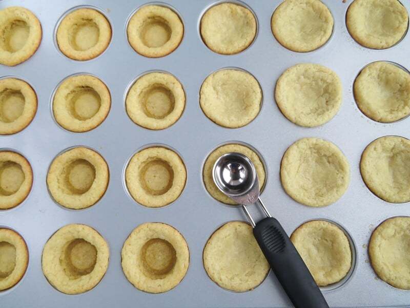 Indent being pressed into cookie cups with measuring spoon.