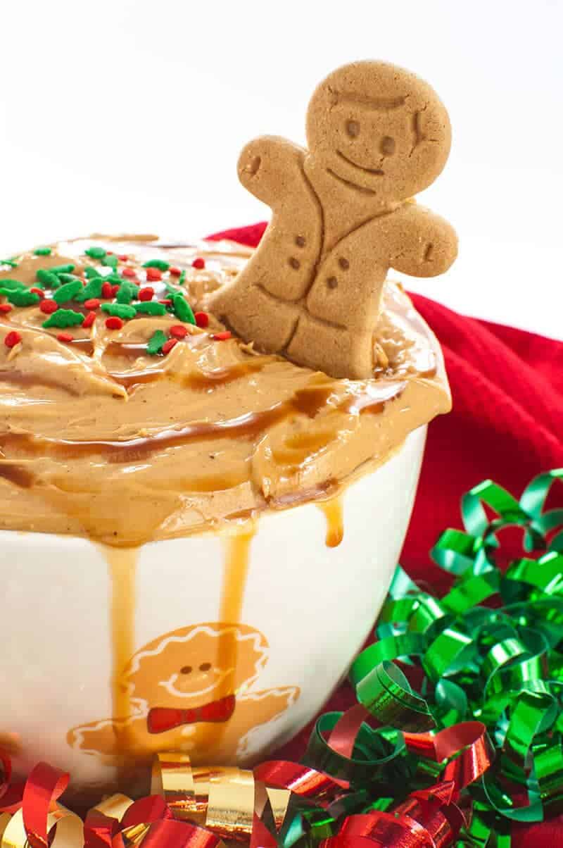 Overflowing bowl of dessert dip topped with sprinkles and a gingerbread man