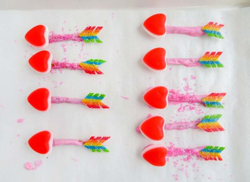 Completed candy arrows on lined baking sheet, some with pink sanding sugar sprinkled onto body of arrow and some without.