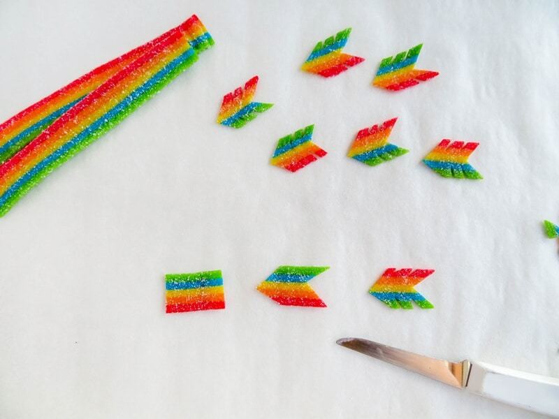 Rainbow candy being cut into the shape of feather at end of arrow.