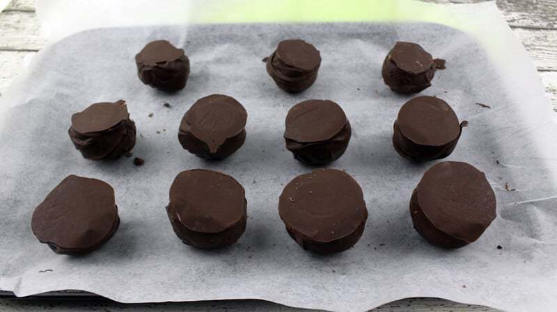 Chocolate covered balls upside down on lined baking sheet.