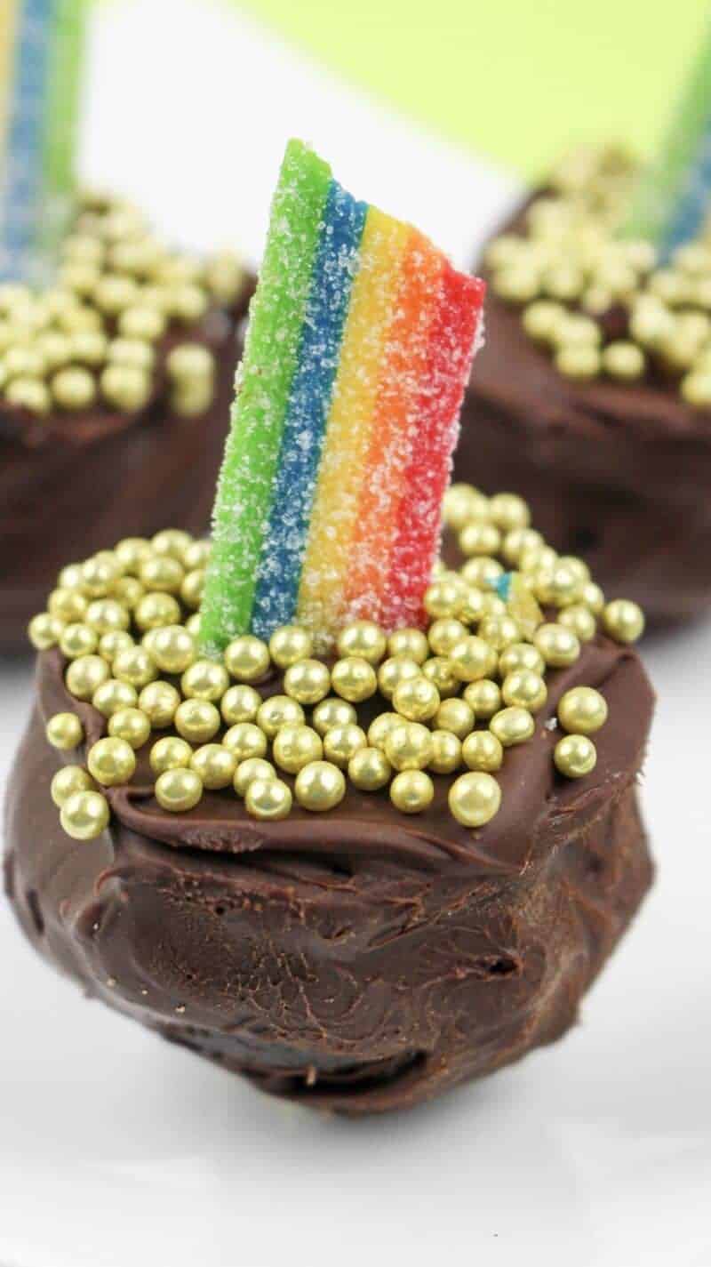 Close up of a pot of gold oreo truffle with rainbow candy and small gold balls on top.