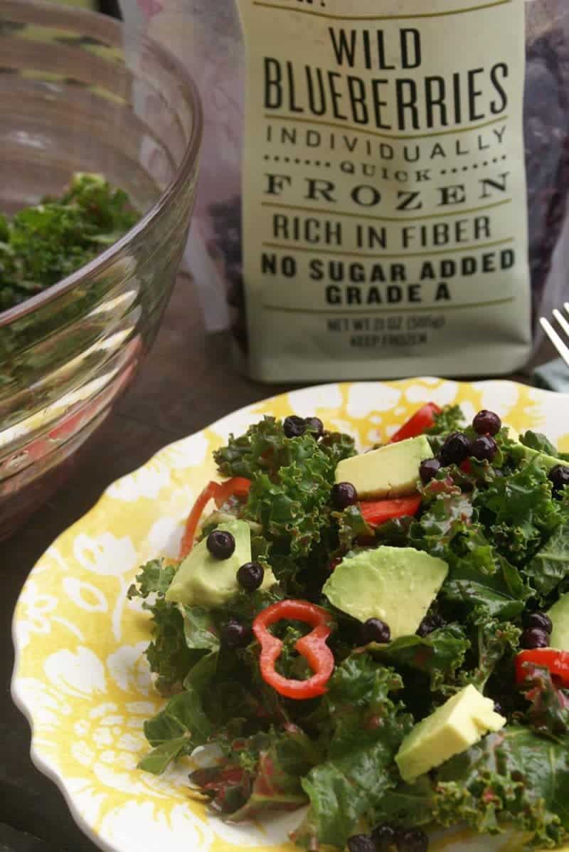 Kale salad with blueberries, avocado, and red chili peppers.