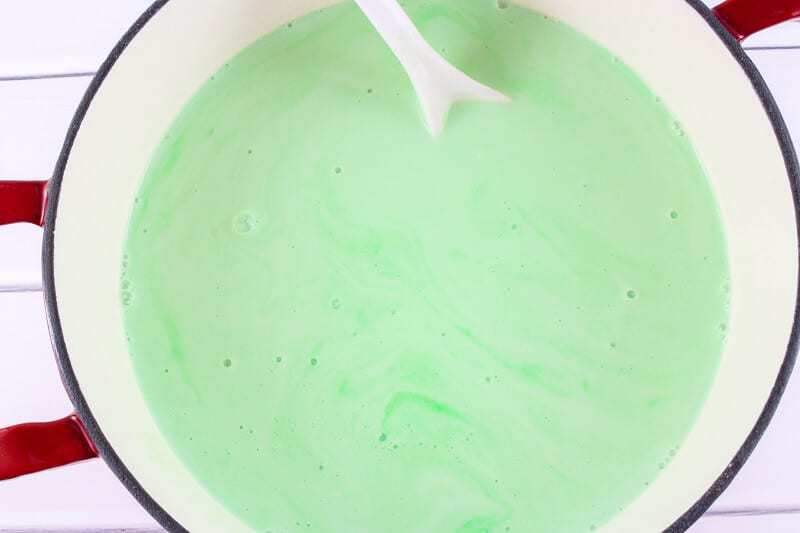 Pot with green creamy liquid and white spoon.