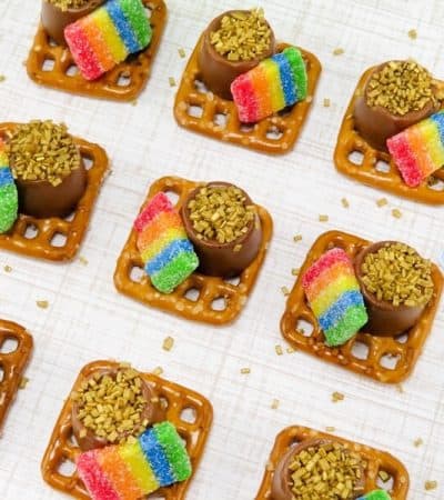 St. Patrick's Day pretzel bites made from square pretzels topped with rolo candies, gold sprinkles, and rainbow airheads.