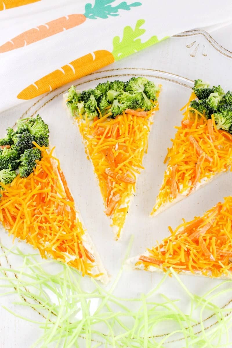 Crescent roll veggie pizza bars topped with shredded carrots and broccoli, arranged to look like carrots.