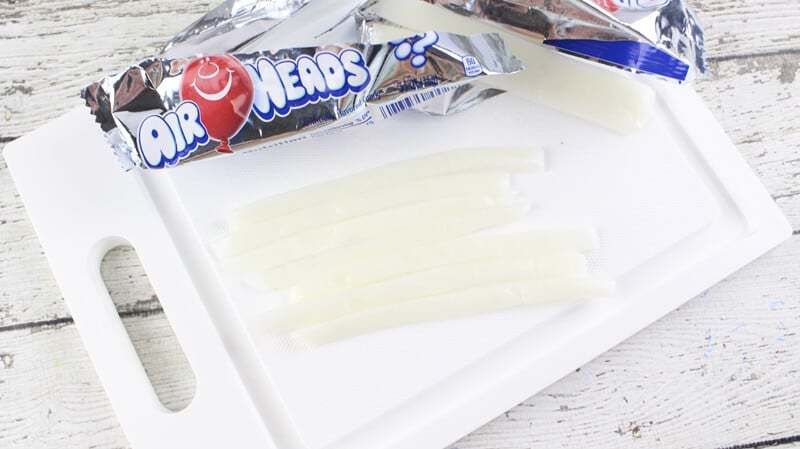 Half inch long strips of white airhead candy on cutting board.