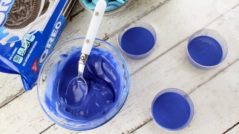 Melted blue candy melts in a glass bowl and added in the bottom of three candy molds.
