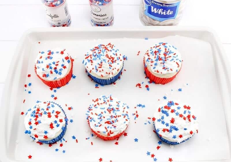 Vanilla cupcakes with white frosting and patriotic sprinkles.
