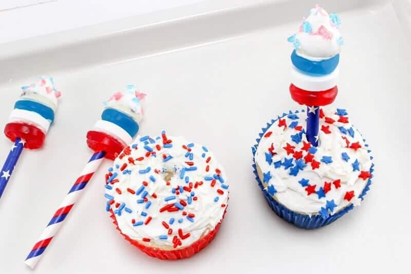 Firecracker cupcakes toppers being pushed into top of cupcake.
