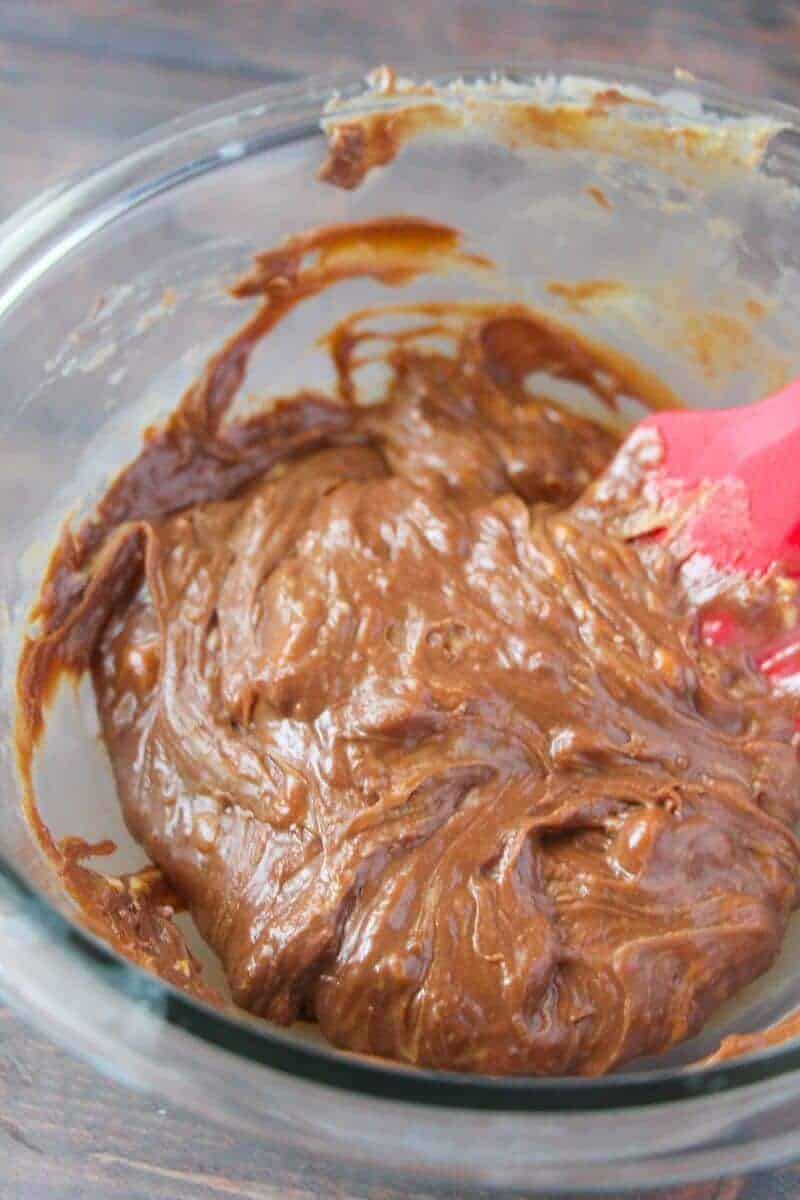 Melted ingredients being stirred together with a silicone spatula in glass bowl.