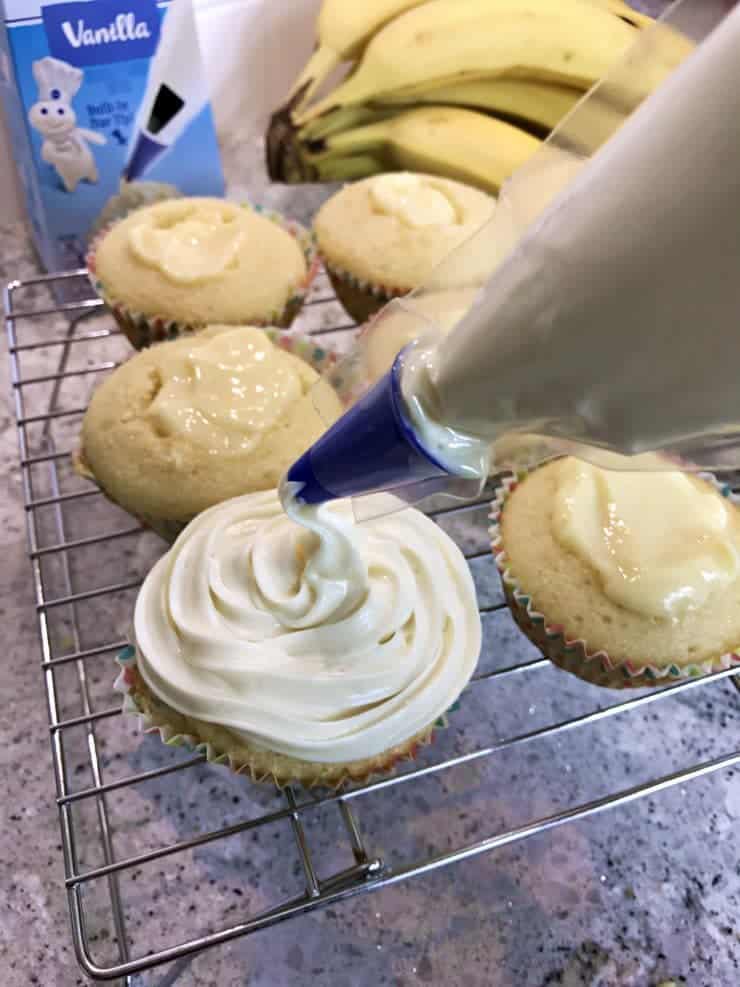 Vanilla icing being piped on the cupcakes. 