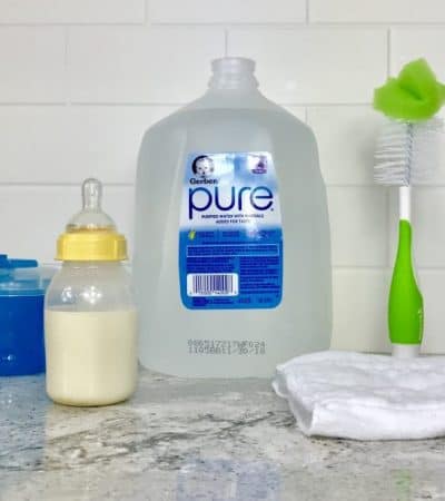 Bottle of baby formula along with bottle feeding supplies on countertop.