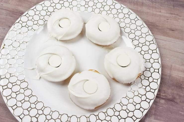 White coated doughnuts with white candy covering the hole in center.