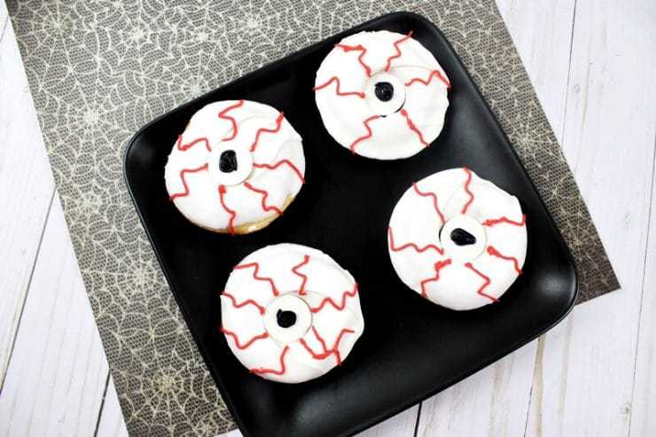 Finished monster eyeball bloodshot donuts on black plate.
