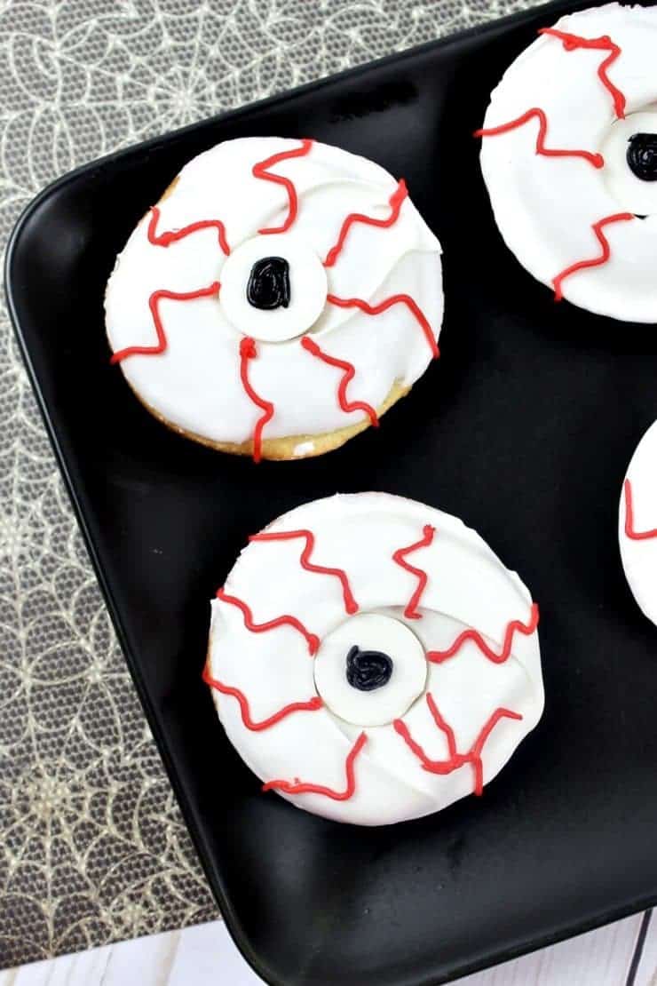 Bloodshot monster eyeball donuts on black plate.