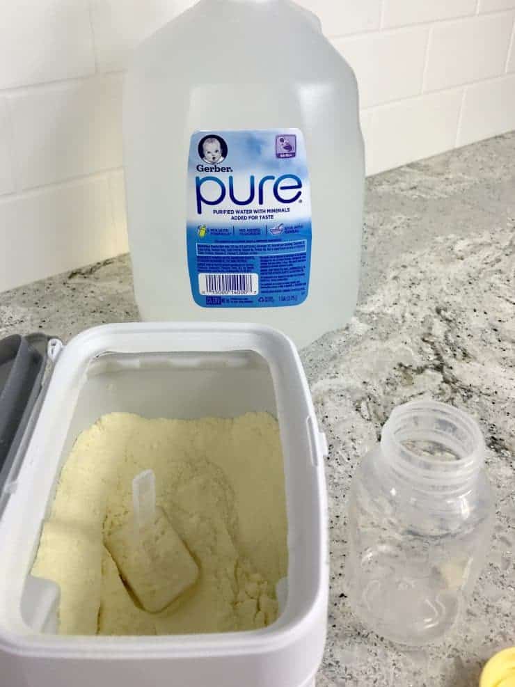 Bottle of nursery water, baby bottle, and container of infant formula.