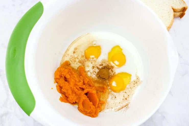 Eggs, pumpkin spice, pumpkin puree and milk in a mixing bowl.