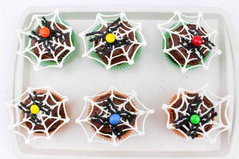 Spider web cupcakes on baking sheet.
