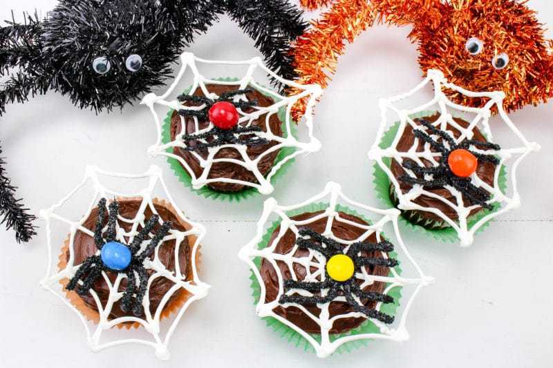 Spider web cupcakes next to two spider decorations.