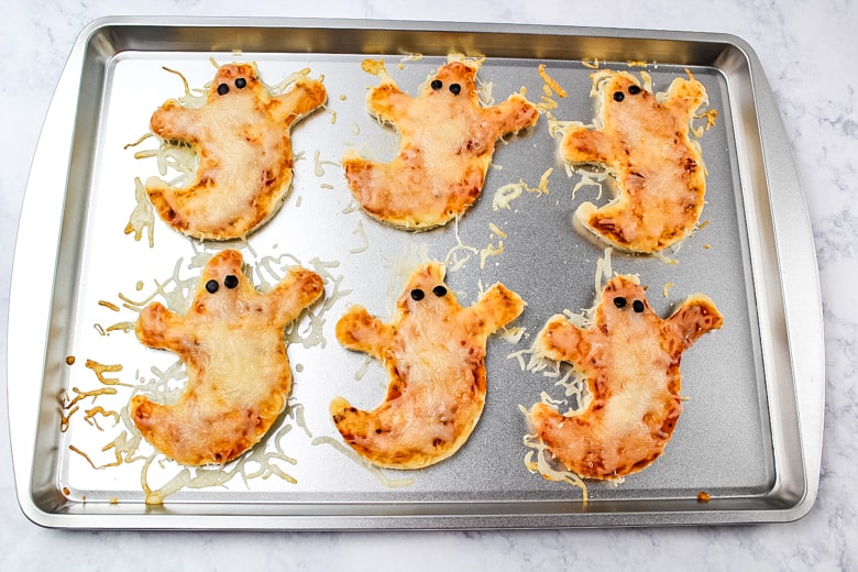Ghost Pizzas on baking sheet fresh from the oven with cheese melted.