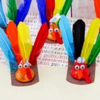 A group of colorful turkey crafts made from Hershey’s Kisses with feathers and googly eyes.