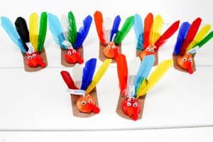 A group of colorful turkey crafts made from Hershey’s Kisses with feathers and googly eyes.