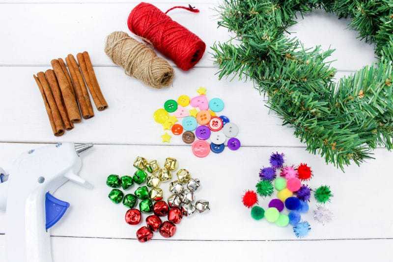 A fun DIY Christmas Tree Ornament craft, made using wreath garland, cinnamon sticks, twine, buttons, pom poms and jingle bells.