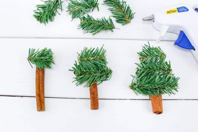 A fun DIY Christmas Tree Ornament craft, made using wreath garland, cinnamon sticks, twine, buttons, pom poms and jingle bells.