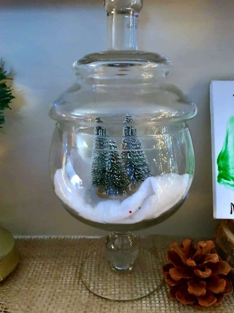 Looking for an easy Christmas mantle decor idea? This cheery mantle decorated with glass jars, lanterns, and pinecones is perfect for Christmas and winter in general.