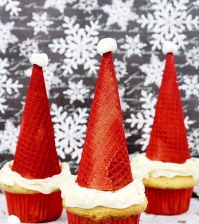 Santa hat cupcakes are made by topping cupcakes with red sugar cones and a mini marshmallow. These fun and easy Christmas cupcakes will definitely be a hit!