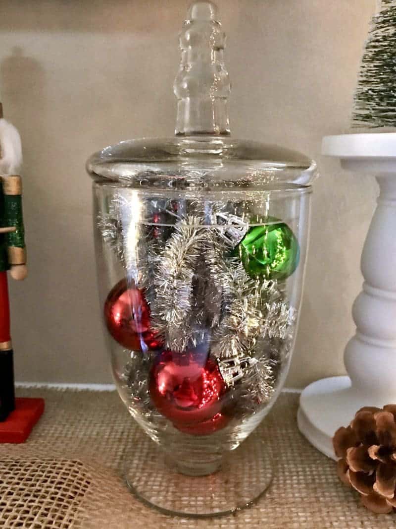 Looking for an easy Christmas mantle decor idea? This cheery mantle decorated with glass jars, lanterns, and pinecones is perfect for Christmas and winter in general.