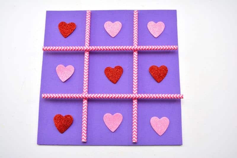 This DIY Tic Tac Toe board game is an easy Valentine's Day homemade craft for the kids to make using a foam sheet, paper straws, and pink and red hearts.