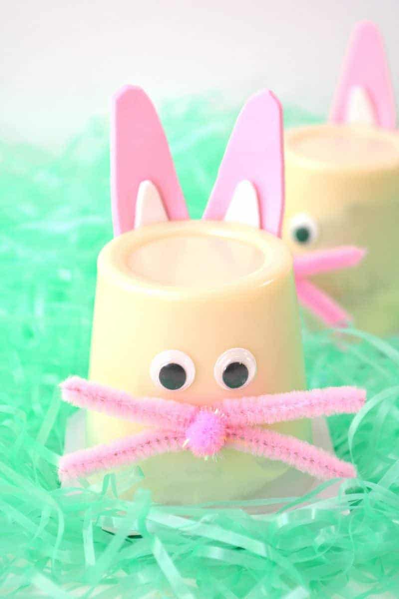 Vanilla pudding cups decorated with pink and white foam ears, googly eyes, a pom-pom nose, and pink pipe cleaner whiskers.