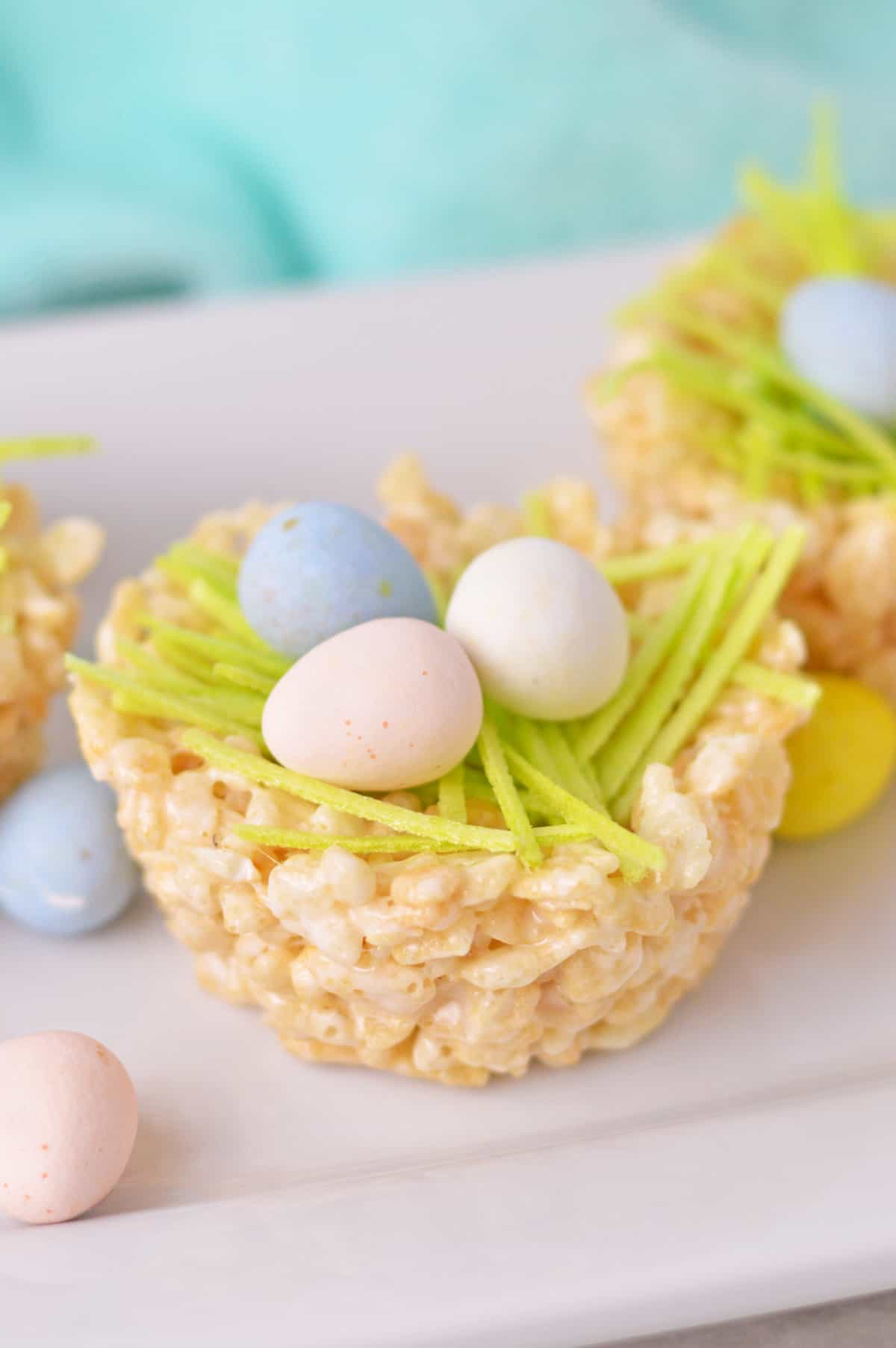 Rice Krispie Nests made with rice krispy treats formed into nests shapes and filled with edible green grass and chocolate mini eggs.