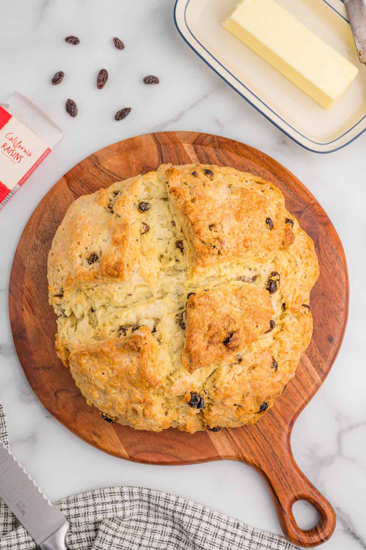 Overhead view of Irish soda bread with raisins and caraway seeds on a wooden board