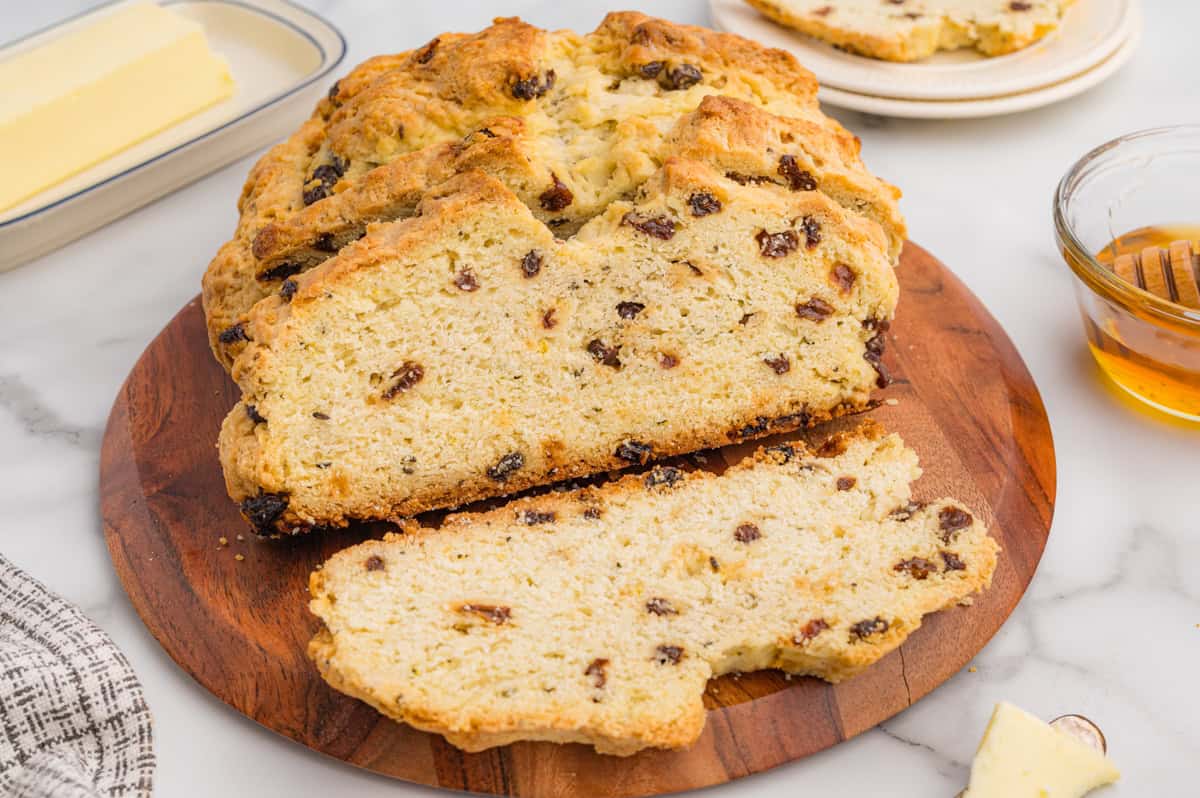 Loaf of Irish soda bread with raisins on a wooden cutting board