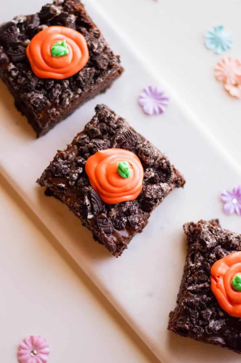 Chocolate brownies topped with crushed oreos and melted chocolate carrot tops.