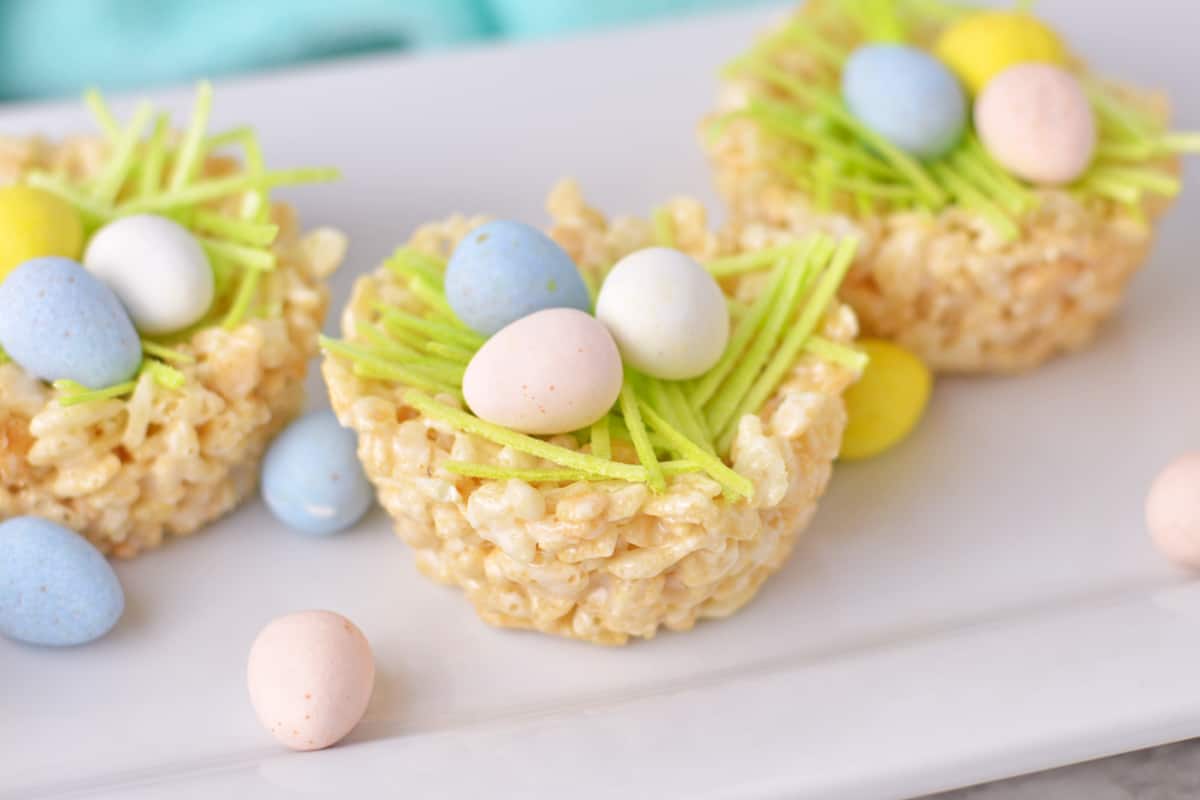 Three rice krispie nests with mini eggs and edible grass.
